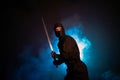 Medieval warrior assassin ninja with sword in aggressive pose in smoke Royalty Free Stock Photo