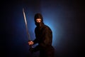 Medieval warrior assassin ninja with sword in aggressive pose in smoke Royalty Free Stock Photo