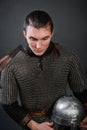 A medieval warrior in chain mail sits on his knee with a helmet in his hands. Knighting Royalty Free Stock Photo