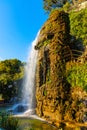 Waterfall off rocky cliff of Colline du Chateau Castle Hill over Mediterranean Sea shore in historic district of Nice in France