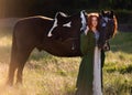 Medieval woman princess in green dress sits astride black steed horse.