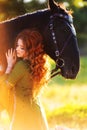 Medieval woman princess in green dress sits astride black steed horse.