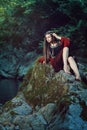 Medieval young lady on a stream rock