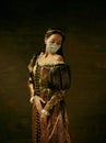 Medieval young woman as a duchess wearing protective mask against coronavirus spread