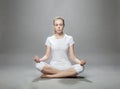 Meditating blonde woman on gray background