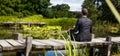 Meditating businessman relaxing on wooden path above water