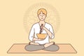 Meditating man sitting in lotus position on yoga mat using bowl to perform ancient ritual