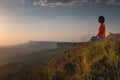 meditating woman sitting in lotus position near a cliff at sunset overlooking the mountains, practice in yoga, peace of Royalty Free Stock Photo