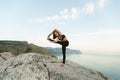 Meditation in a complex yoga pose on a huge stone overlooking the sea and mountains. Royalty Free Stock Photo