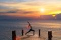 Meditation girl on the sea during sunset on the wood the bridge.