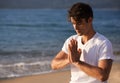 Meditation, hands with prayer and man on beach, mindfulness and zen with fresh air for calm outdoor. Ocean, seashore and Royalty Free Stock Photo