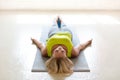 Meditation and pilates practice. Caucasian woman lying on the floor in shavasana with her feet up on a small ball in the Royalty Free Stock Photo