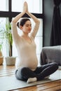 Meditation during pregnancy. Young calm tranquil pregnant woman doing yoga and meditating at home Royalty Free Stock Photo