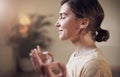 Meditation takes practice and patience. an attractive young woman sitting alone and meditating indoors.