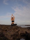 Meditation yoga on the beach. Asian woman sitting on the rock in Lotus pose. Padmasana. Hands raised up in namaste mudra. Yoga Royalty Free Stock Photo