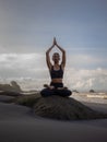 Meditation yoga on the beach. Asian woman sitting on the rock in Lotus pose. Padmasana. Hands raised up in namaste mudra. Yoga Royalty Free Stock Photo