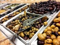 Mediterranean black and green olives in olive bar metal trays with serving spoons