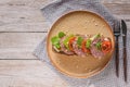 Mediterranean breakfast or lunch. Bruschetta with salami and tomatoes, cream cheese, pea microgreens and pesto sauce on a ceramic