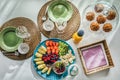 Mediterranean breakfast overhead top view with muffins, coloured spring seasonal fruits on straw mats and white wooden background