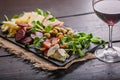 Mediterranean delicious and tasty snacks. Assorted cheeses, sausages, smoked meat, lettuce, bread, olives, glass of red wine and Royalty Free Stock Photo