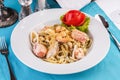 Creamy pasta with shrimps, crab meat, seafood, squid rings, tomatoes, basil, greens and cheese. Royalty Free Stock Photo
