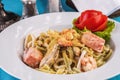 Creamy pasta with shrimps, crab meat, seafood, squid rings, tomatoes, basil, greens and cheese. Royalty Free Stock Photo