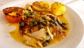 Mediterranean fish dish with caper sauce, passion fruit and tomato sauce, potatoes, hearts of palm and grilled onions