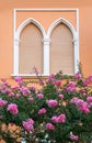 Mediterranean house facad with arched window and closed shutters, blooming tree