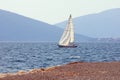 Mediterranean landscape with one sailboat with white sail on water. Montenegro, Adriatic Sea. View of Kotor Bay near Tivat city