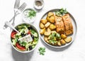 Mediterranean lunch table - baked lemon salmon with potatoes, greek salad, tzadziki sauce on light background, top view. Flat lay