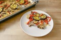 Mediterranean oven vegetables baked in olive oil with herbs and spices on a plate and on a baking tray, wooden table, vegetarian Royalty Free Stock Photo