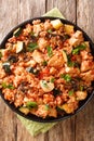Mediterranean rice with chicken, zucchini and mushrooms in tomato sauce close-up in a frying pan. vertical top view