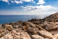 Mediterranean Sea in Northern Cyprus. Summer rocky coast, transparent calm blue water and white clouds on blue sky. Seascape.