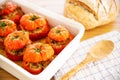 Mediterranean stuffed tomatoes with meat and bread crumb  in a white dish, with kitchen towel and bread loaf Royalty Free Stock Photo