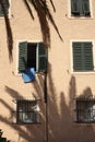 Mediterranean style building with open and close jalousies with a blue towel hanging out of the window