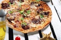 Mediterranean style flatbread pizza, on a white wooden boards, table. Freshly baked flatbread with Italian ingredients.