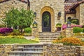 Mediterranean style rock house entrance with arched porch and two flights of steps and tiled roof - lanscaped with laterns Royalty Free Stock Photo