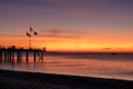 Mediterranean sunrise with pebble beach and pier silhouette