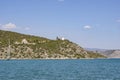 Mediterranean travel scene with boat and church and old windmill on distant hill