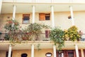 Mediterranean Two-storid building with columns and open balcony with flowering trees in pots, summer terrace with potted plant nea