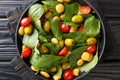 Mediterranean vegan salad of spinach, lupine beans, tomatoes and olives close-up in a plate. horizontal top view
