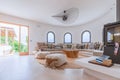 Mediterranean villa living room with portholes windows, sofa along the circumference, with numerous cushions, 2 ottomans