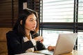 Attractive young Asian woman in formal suit is working with laptop  on table next window, she is looking outside while thinking Royalty Free Stock Photo