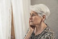medium close up shot older lady with dementia standing next to the window and worrying about life Royalty Free Stock Photo