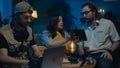 Medium-full photo capturing two ghost hunters and a victim sitting at the table. The woman is showing a framed photo