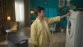 Medium-full shot. Dark-haired man standing next to a washing machine, starting a program after loading the laundry into Royalty Free Stock Photo
