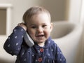 Medium horizontal shot of fair smiling toddler girl holding a toy phone receiver to her ear