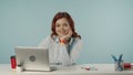 Medium isolated shot of a satisfied, happy and relaxed young woman sitting at the desk with laptop and working supplies