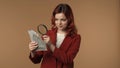 Medium isolated shot of a young woman looking at bills in her hand through magnifying glass and smiling. Money and cash