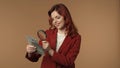 Medium isolated shot of a young woman looking at bills in her hand through magnifying glass and smiling. Money and cash